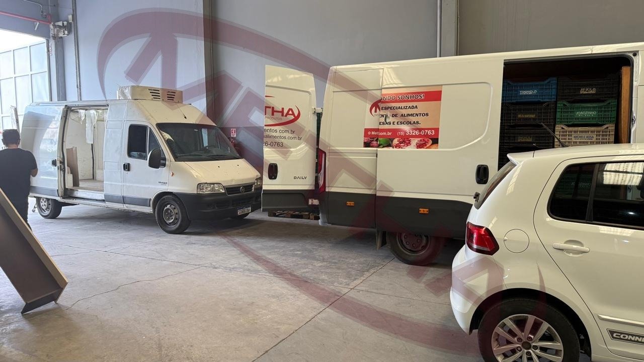 Frota de vans da Metha Alimentos no galpão